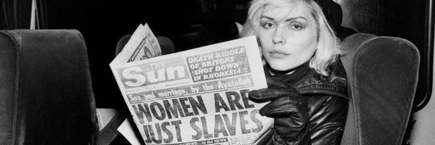 Debbie Harris holding a newspaper that says women are just slaves